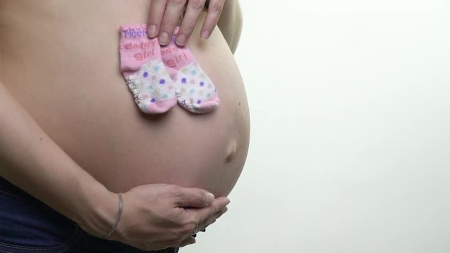 Lovely shooting of a pregnant woman that put baby socks to her tummy