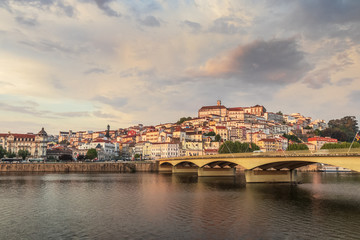 Coimbra at sunset on a spring day, with Mondego river and bridge in foreground, in Portugal.