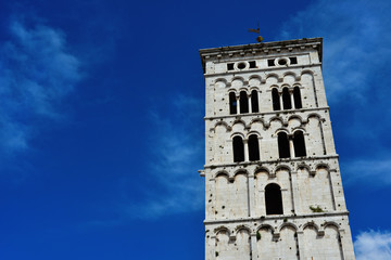 Fototapeta na wymiar Saint Micheal in Foro Church medieval romanesque bell tower, erected in the 13th century in the city of Lucca, Tuscany (with blue sky and copy space)