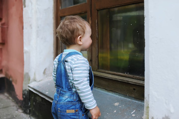 The little boy looks at the reflection in a window of the city building