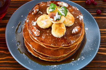 Pancakes with caramel, banana and nuts decorated with cranberries and mint with juice.