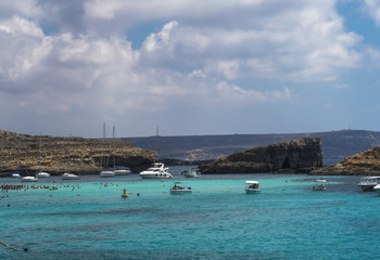 Fototapeta na wymiar Comino Island, Malta pleasure boats moored at the Blue Lagoon. The most famous and crowded beach in Malta with crystal clear waters.