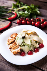 Salad with meat, cheese and tomatoes on a wooden background