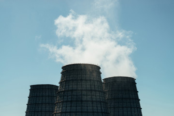 Two big tower of CHPP close-up. White steam from wide pipe of CHP on blue sky. Industrial background image of TPP with copy space. Huge pipes of thermal power plant produce steam for electric power.