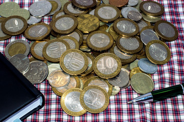 black notebook, coins and pen on checkered background