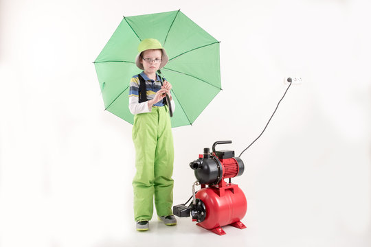 Happy boy in green clothers with red deep well pump. Concept of family business. White background
