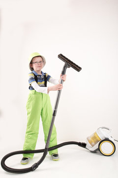 Happy boy in green clothers with vacoom cleaner in studio. white background