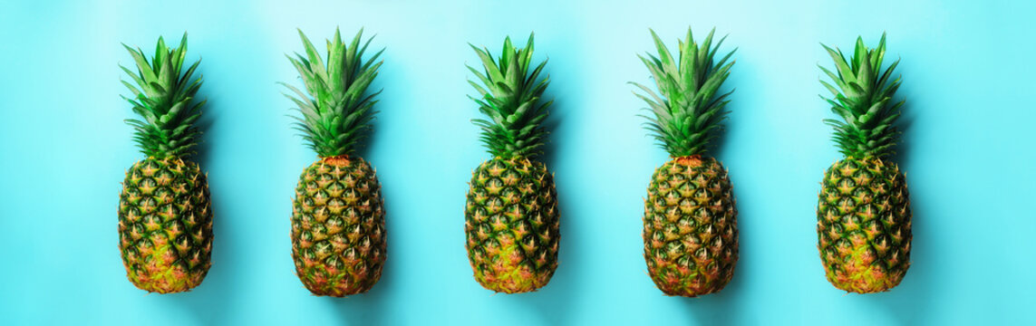 Bright pineapple pattern for minimal style. Top View. Pop art design, creative concept. Copy Space. Fresh pineapples on blue background. © jchizhe