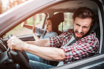 Bearded man is driving car. They are riding too fast. Guy is keeping his eyes closed but still driving car. Girl is keeping her hands in front of her. She is trying to defence herself.