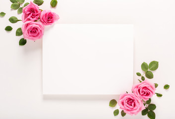 Roses and blank greeting card top view flat lay