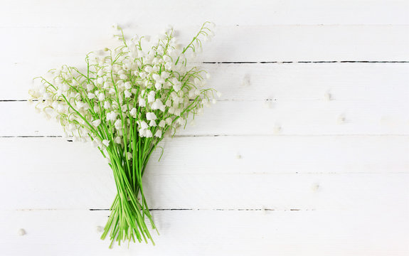 bouquet of Lily of the valley flowers closeup on white wooden table with copy space