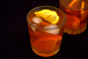 Iced tea with lemon and orange on the black background. Refreshment
