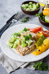 Close-up of Grilled chicken breast with tomato and pepper grill and salsa from avocado and cucumber on plate on stone gray table background. Healthy Clean Diet Dinner Concept