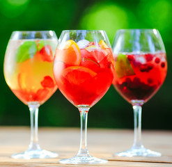 Summer cocktail. Fruit cocktail on green background. Citrus fruits, berries, strawberries, blueberries, mint, ice.