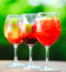 Summer cocktail. Fruit cocktail on green background. Citrus fruits, berries, strawberries, blueberries, mint, ice.