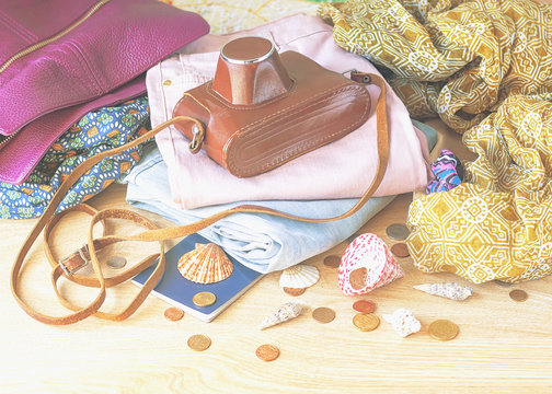 Outfit of young woman. Vintage camera, women's clothing, seashells and passport on wooden background.