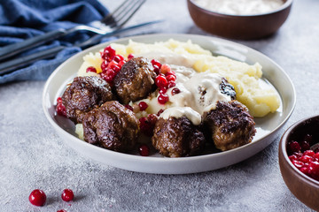 Homemade beef and pork meatballs with mashed potatoes and lingonberry sauce on a gray stone...