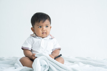 cute little asian boy sitting on soft blanket