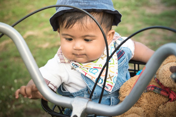 Cute asian baby sitting in bicycle basket,vintage tone