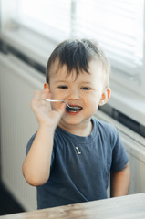 The little boy in the kitchen eagerly eating rice with a spoon independently