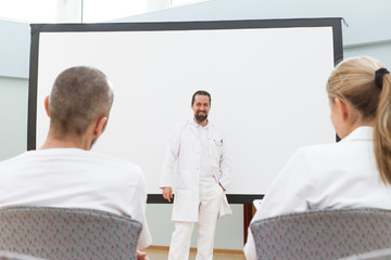 Medizinstudenten bei einer Besprechung, Vortrag oder Seminar, Arzt neben Leinwand