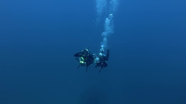 Two scuba divers man and woman swims in the blue water, Indian Ocean,  Maldives
