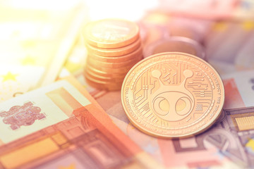 shiny golden ANTSHARES cryptocurrency coin on blurry background with euro money