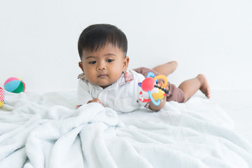 cute asian baby lying on soft blanket and play ball