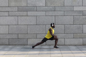 Afro american jogger doing stretching after morning workout.
