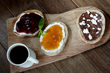 Homemade Chocolate-Hazelnut Spread on bread with strawberry and apricot jam in wooden backdrop.