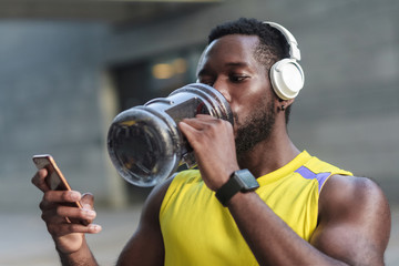 Active lifestyle. Strong african man drinking water after hard workout