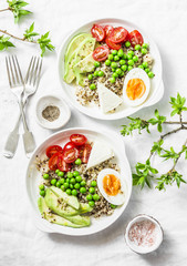 Savory  breakfast grain bowl. Balanced buddha bowl with quinoa, egg, avocado, tomato, green pea on light background. Healthy diet food concept. Top view, flat lay