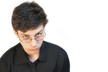 Portrait of a sad teenager in glasses and a dark shirt on a white background. A boy is sad because he does not like to wear glasses to improve his vision
