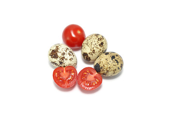 Quail eggs and red tomato on white closeup background 