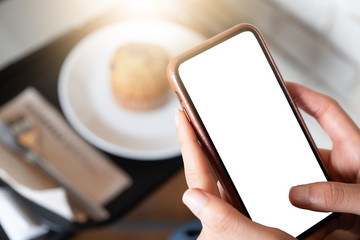 Close up of women's hands holding cell telephone with blank copy space scree for your advertising text message or promotional content, hipster girl watching video on mobile phone during coffee break