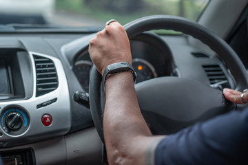 back side of aman driving in a car and smart watch in his hand