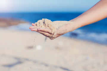 Fototapeta na wymiar Sand running through hands on beach