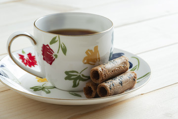 A cup of tea and coconut rolls on wooden background