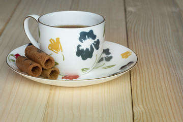 A cup of tea and coconut rolls on wooden background