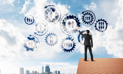 Businessman on house roof presenting teamwork and connection concept. Mixed media