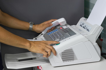 hand man are using a fax machine in the office. Business concept 