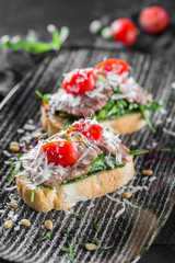 Italian bruschetta with tuna and tomatoes. Served on a black plate