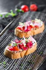 Italian bruschetta with salmon and tomatoes. Served on a black plate
