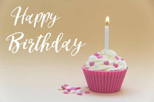 pink birthday cupcake with candle on beige background