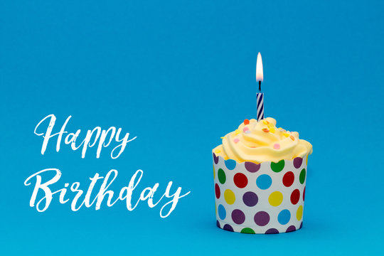 colorful birthday cupcake with candle on blue background