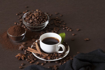 Сoffee in white cup coffee beans and ground powder on brown background.