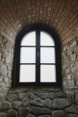 Fototapeta na wymiar Arched window on the wall of the medieval fortress
