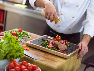 Chef finishing steak meat plate