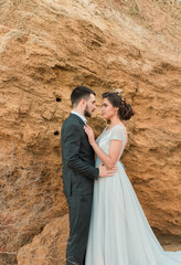 Wedding bride and groom with bouquet posing near sea on sunset