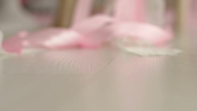 Close-up of pink and white silk ribbon on white background, they fly away from the wind. Slow motion.